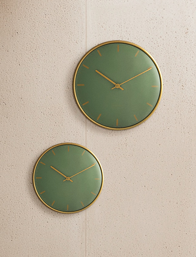 Zwei Arne Jacobsen City Hall Wanduhren in Grün mit goldenfarbenen Zeigern an heller Betonwand