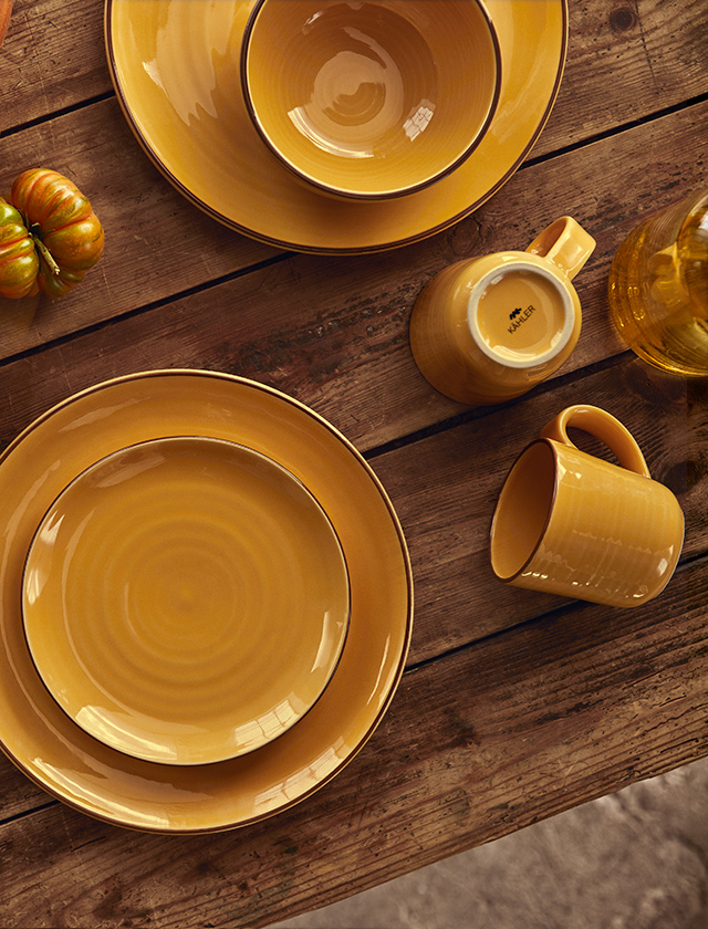 Tisch mit der Colore Geschirrserie von Kähler Design in Saffron Yellow  Frühstücksteller & Essteller, Müslischalen und Becher mit Henkel aus Keramik.