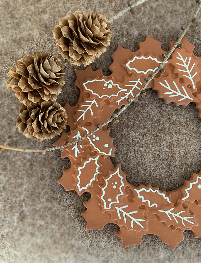 Dieses Bild fängt die Essenz der Winterzeit mit einem kunstvoll gestalteten Gingerbread Kranz von Kähler Design ein. Der Kranz, der detailreich aus Keramik gefertigt wurde, zeigt Motive, die an den klassischen Lebkuchen mit weißem Zuckerguss erinnern. Er ist sorgfältig mit Mustern aus Blättern und abstrakten Verzierungen geschmückt, was ihm ein festliches und gleichzeitig elegantes Aussehen verleiht.