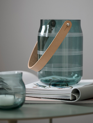 Die Omaggio Glaslaterne in Moosgrün von Kähler Design können Sie auf dem Esstisch, Ihrem Sideboard oder auf Ihrer Terrasse platzieren. Durch den schönen Grünton des Glases fällt ein warmes, stimmungsvolles Licht. Der Lederhenkel aus Kernleder ermöglicht sogar das aufhängen der Laterne.