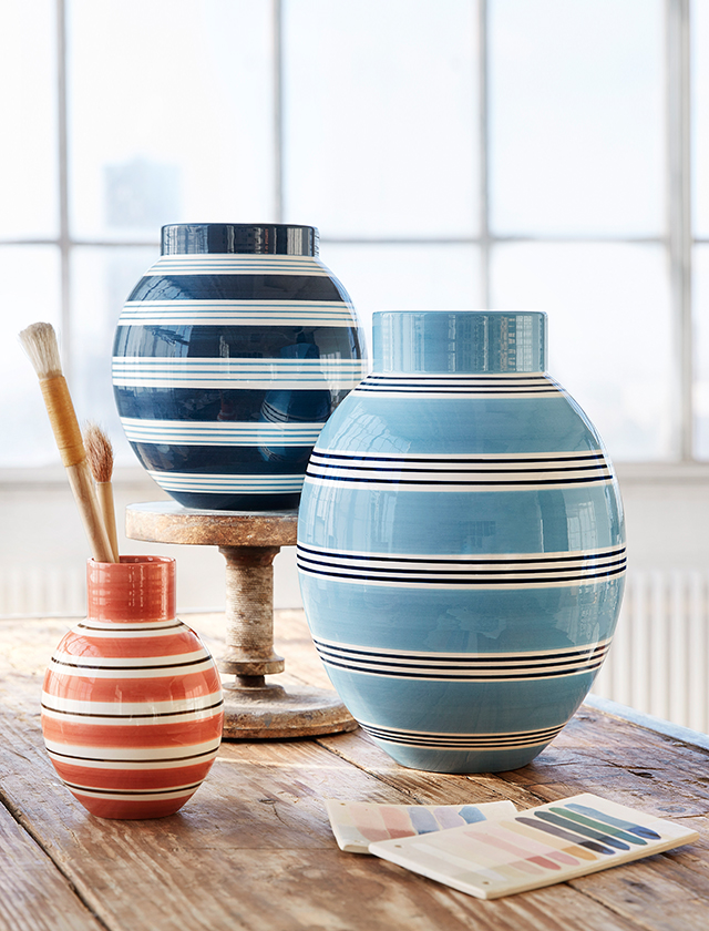 Die Omaggio Nuovo Vasen sind in den Farbvarianten Blau mit dunkelblauen Streifen, Dunkelblau mit blauen Streifen und Terrakotta mit braunen Streifen von Kähler Design