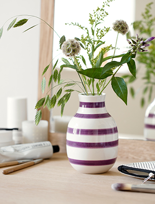 Omaggio Vase Pflaume von Kähler Design in der kleinen Größe. Ihre violetten Streifen bilden einen raffinierten Kontrast zum weißen Grundton und passt perfekt zu sommerlichen und herbstlichen Blumenarrangements.