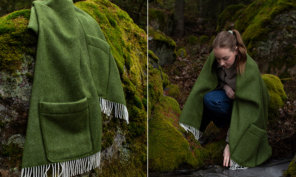 Arvo Pocket Shawl von Lapuan Kankurit aus Finnland in einer wunderschönen olivgrünen Farbe mit weißen Fransen an den Enden. Auf der linken Seite sieht man den Schal, der über einen moosbewachsenen Felsen gelegt ist, wodurch die feine Webstruktur und die praktischen Taschen gut zur Geltung kommen. Auf der rechten Seite ist eine junge Frau abgebildet, die den Schal um ihre Schultern gewickelt hat. Sie sitzt in einer natürlichen Umgebung, was die vielseitige Nutzung des Schals im Freien betont.