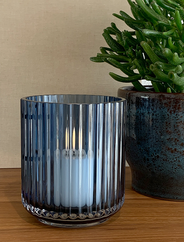 Lyngby Windlicht in Midnight Blue besticht durch seine Eleganz und Funktionalität. Das mundgeblasene Glas mit seinen markanten Rillen fängt und reflektiert das Licht auf eine Weise, die dieses Stück sowohl als praktisches Beleuchtungselement als auch als ansprechendes Dekorationsobjekt erscheinen lässt. Seine tiefblaue Farbe und die sorgfältige Gestaltung zollen dem legendären Design der Lyngby Vase Tribut, das seit Jahrzehnten Designliebhaber auf der ganzen Welt begeistert.