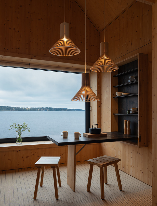 Drei Secto Design Puncto 4203 Pendelleuchten aus Holz über einem Tisch in modernem skandinavischem Interieur mit Seeblick